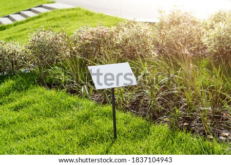 Empty sign board on grass with space for caption. Property house for sale sign board. Notice board with copyspace for prohibition