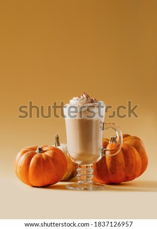 Spice pumpkin latte in glass with pumpkins on yellow background, copy space, top view