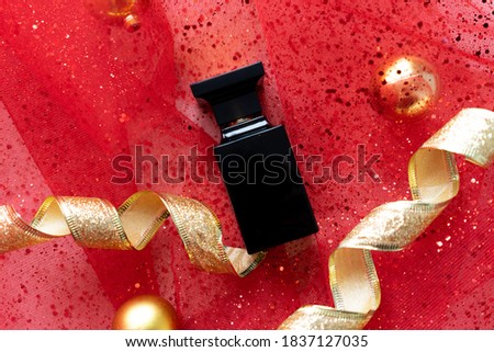 
black perfume bottle on red background with sparkles and gold balls. concept of new year perfume