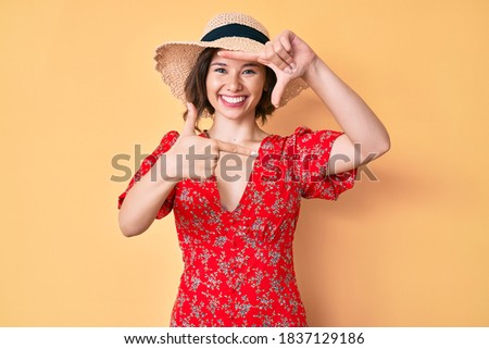 Young beautiful girl wearing summer hat smiling making frame with hands and fingers with happy face. creativity and photography concept. 