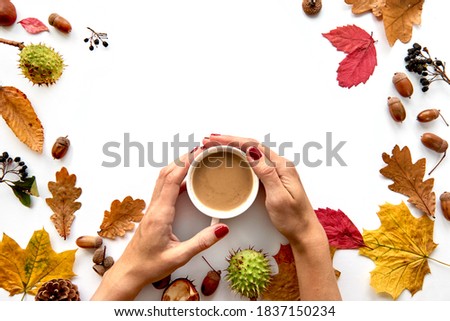 Autumn composition. Frame made of dried leaves, branches, pine cones, berries, acorns and hand with cup of coffee on white background. Template mockup fall, halloween. Flat lay, copy space background
