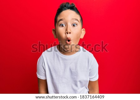 Little boy hispanic kid wearing casual white tshirt scared and amazed with open mouth for surprise, disbelief face  Royalty-Free Stock Photo #1837164409