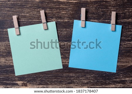 Empty colored paper sheets for notes with clothespins on wooden background. Blank cards on mockup template. Wooden clothespins with sheets of paper. Business concept, copy space