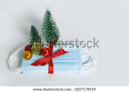Medical mask as gift with a red ribbon and ornament on white background, COVID 19 protection ,The concept of health care in the Christmas Festival