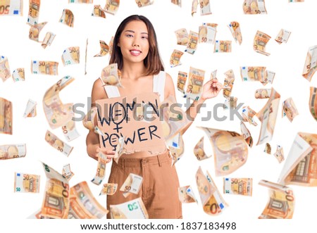 Young beautiful chinese girl holding woman power banner smiling happy pointing with hand and finger to the side