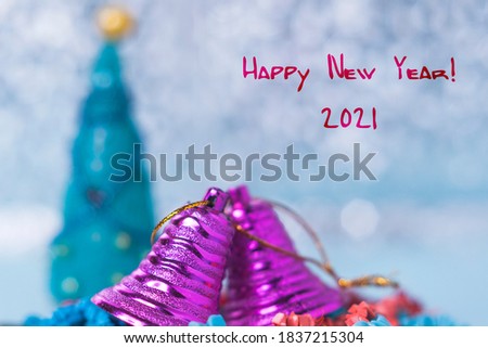 Christmas or new year card. Two lilac Christmas bells on a blue bokeh background. Happy new year sign! Selective focus.