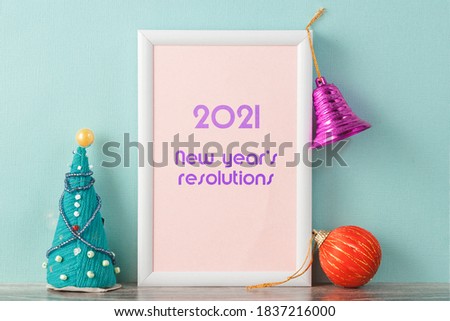 Caption in photo frames New year resolutions 2021. To the right and left of the frame are Christmas decorations.