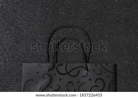 Shopping bag with empty space for text on black background. Black Friday backdrop. Deal concept. Mock-up for conceptual message. Top view. Flat lay
