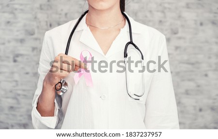 Doctor with pink ribbon and stethoscope on white background, close up. Breast cancer awareness. Healthcare and medicine concept girl doctor in medical gown with pink breast cancer awareness ribbon