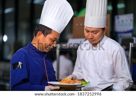 The male executive chef discussing the menu with his colleague in the kitchen. Royalty-Free Stock Photo #1837252996