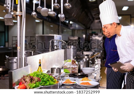 The male executive chef discussing the menu with his colleague in the kitchen. Royalty-Free Stock Photo #1837252999