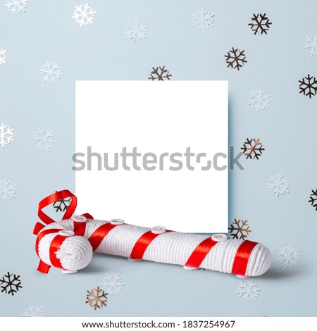 White paper card decorated with snowflakes on blue background. New Year, Christmas and winter concept. Flat lay, top view, free copy space