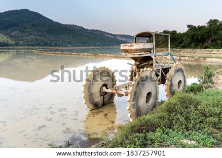 Flooded rice plantation with reflection of the mountains and a tractor inside