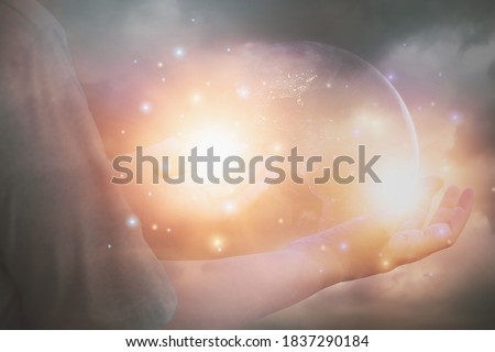 Glittering light shine through hand women,who raise hands,to pray for God blessing,planet and sunset background mind sanctification,concept pure spirit and spirituality,Element image furnished by NASA