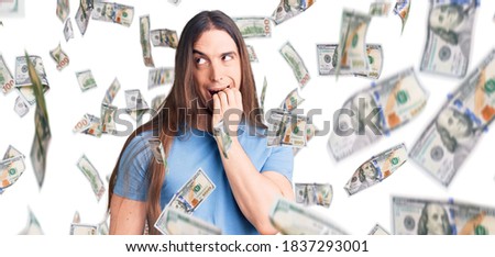 Young adult man with long hair wearing casual clothes looking stressed and nervous with hands on mouth biting nails. anxiety problem.