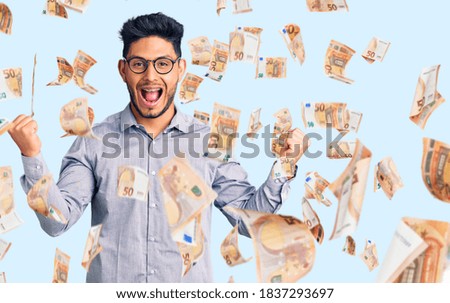 Handsome latin american young man wearing business clothes and glasses screaming proud, celebrating victory and success very excited with raised arms