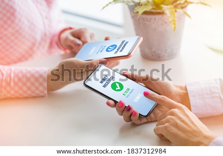 Woman sending money to her friend using mobile phone Royalty-Free Stock Photo #1837312984