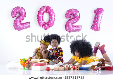 Dark skinned boy and girls with metallic pink number balloons on wall, 2021 Happy new year, white background Royalty-Free Stock Photo #1837313752