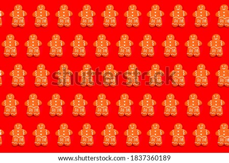 Colorful Gingerbread man pattern on bright red festive background. Tasty homemade Christmas gingerbread man with sugar glaze on bright red festive background. Close up