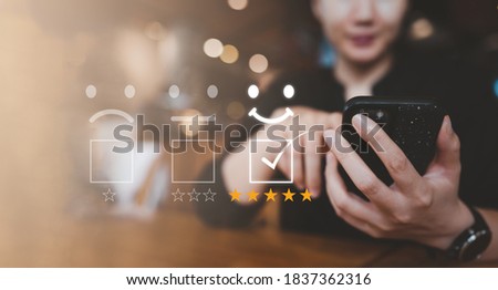 Customer satisfaction concept. female hand holding smartphone Show rating with five stars gold symbol and Smiley Face for her Satisfaction.