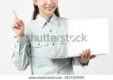 A young woman pointing her index finger while holding a PC with a helmet in work clothes