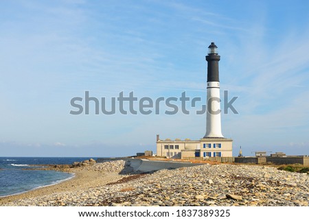 Ile de Sein island rocky coastline of the Atlantic ocean in Brittany, France. Panoramic view. Lighthouse in the background. Idyllic landscape. Travel destinations, tourism, sightseeing, landmarks