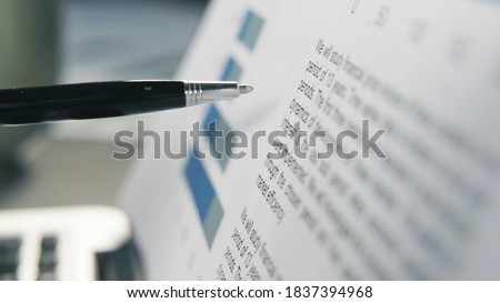 Business university studies, paper with financial text information, closeup. Holding a pen, following the line, research with graphs and analysis, selective focus