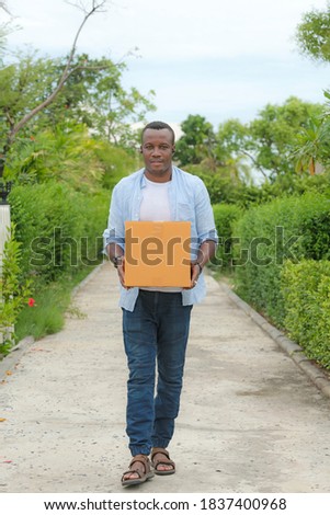 A middle-aged African-American man holding cardboard box sent from a different province. From his online shopping With a smiling face.