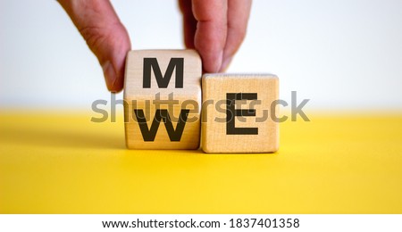 Hand turns a wood cube with me or we words on beautiful yellow table, white background, copy space.  Psychological concept. Royalty-Free Stock Photo #1837401358