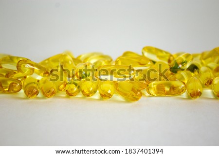 Yellow vitamins tablets, fish oil, Omega Vitamin E. Pills on a blue background. Web banner. Beautiful background. Copy space.
