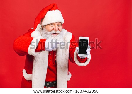 Portrait of nice attractive handsome amazed Santa using phone gadget 5g fast speed blog blogger browsing multimedia isolated over red background.