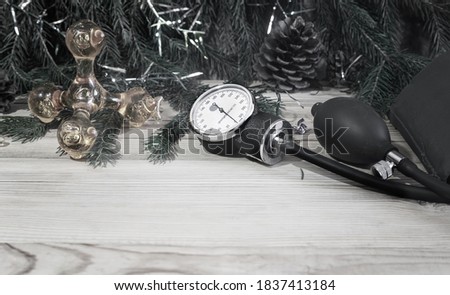 Medical poster with massager, sphygmomanometer and Christmas decorations: garlands, toys, Christmas tree. Copy space. Christmas in medicine.