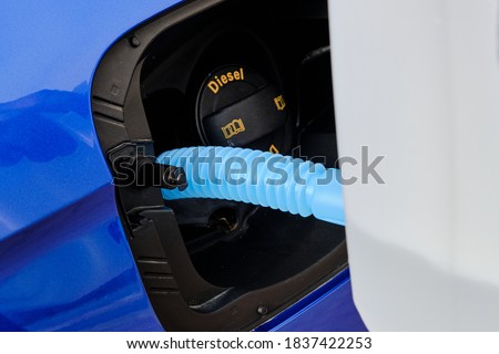 Close up filling of diesel exhaust fluid from canister into the tank of blue car for reduction of air pollution. Environmental or eco friendly solution  Royalty-Free Stock Photo #1837422253