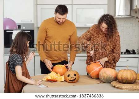 Happy Halloween. Mother, father and their daughter carve a pumpkin. Happy family is preparing for Halloween