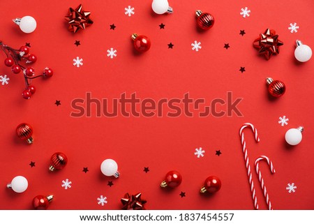 Red Christmas background with baubles decoration, snowflakes, candy canes, confetti. Minimal style, flat lay, top view.