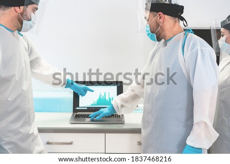 Medical workers in hazmat suit looking laptop computer and talking about coronavirus cases - Soft focus on right doctor's head Royalty-Free Stock Photo #1837468216