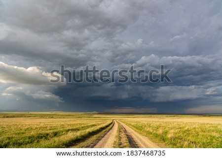 Winding dirt road with a stormy sky in the background