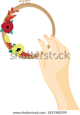 The embroiderer holds one hand on a hoop with beautiful flowers