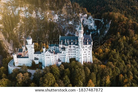 Neuschwanstein castle and bridge in mountains. Sunset panoramic landscape. View from above. Aerial drone photography. Bavaria, Germany. Europe attraction. 