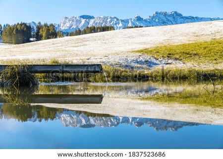 Beautiful tranquil scene in the Dolomites, Italy in a cold winter morning - Scenic landscape reflected on a pond in the Alps at sunrise - Nature, ideal place to isolate and keep social distance