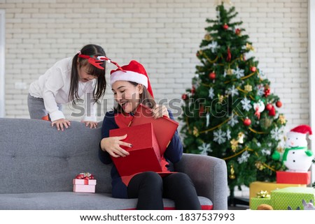 mother and daughter open the gift box together in christmas day at home
