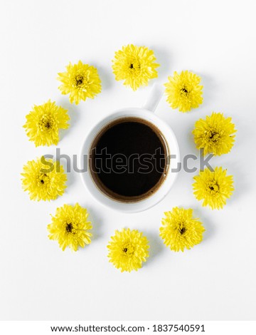 Coffee cup surrounded by yellow Petunia flowers on a white background