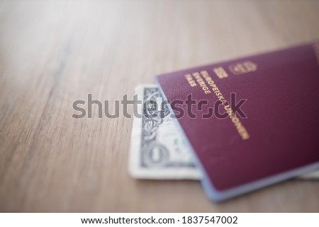European Union, Sweden Passport with a One-Dollar Bill Partially Covered by it