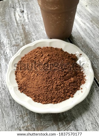 Brown color of cocoa powder in the white plate with chocolate frappe on the old wooden background
