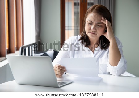 frustrated, shocked, stressed middle aged woman with expensive bill, debt invoice, eviction notice; concept of high cost of living, expensive bill, economic recession, no job no money Royalty-Free Stock Photo #1837588111