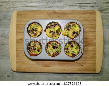 Breakfast egg muffins inside muffin tins. Muffin tin eggs with turkey bacon, mushrooms and green peppers.