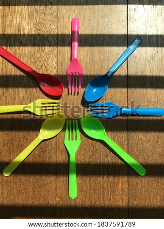 Colorful plastic forks and spoon on wood background