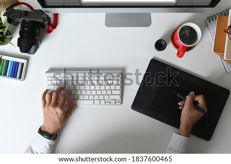Top view of graphic designer hands typing on keyboard and working on graphics tablet.