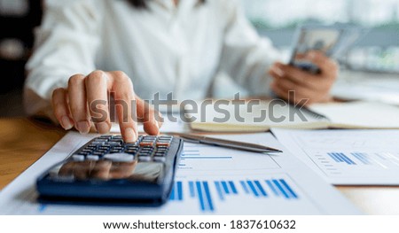 Closeup of business hand using calculator and counting money at home office , graph and us dollar money , savings, finances, economy concept , work at home , business,banking, idea concept