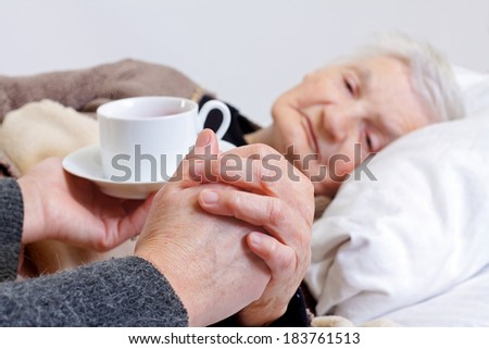 Picture of a woman hand giving tea to an elderly woman